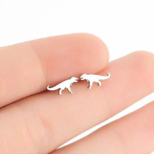 Close-up of a silver-toned dinosaur stud earring held by hand to show compact size