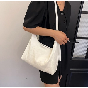 Close-up of a white lychee grain leather hobo bag with adjustable strap on model