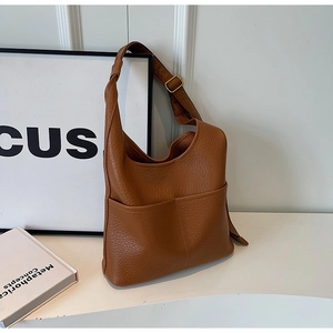 Détail du sac seau en cuir grainé caramel avec boucle dorée et poche latérale pratique