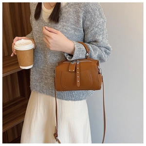 Brown leather Boston bag styled with casual sweater and skirt in a lifestyle setting