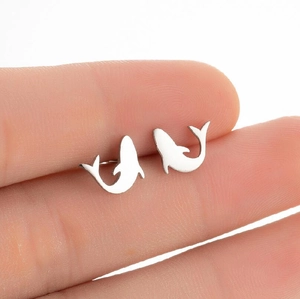 Cute dolphin stud earrings made of polished stainless steel held by hand for scale