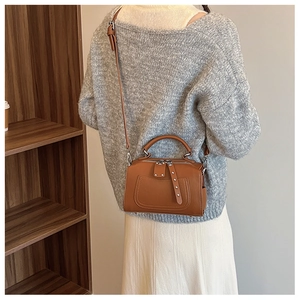 Brown litchi leather Boston bag with tassel detail worn as a crossbody by a model