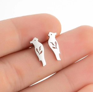 Macro shot of silver bird-shaped hollow stud earrings held by hand on white background