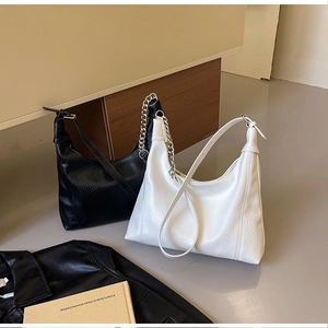 Close-up of black and white textured hobo bags with metallic chain and leather straps