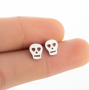Vintage stainless steel skull stud earrings with hollow design shown on fingertip