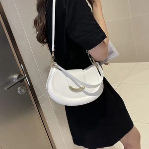 Minimalist white crescent shoulder bag with golden U-shaped buckle on a female model