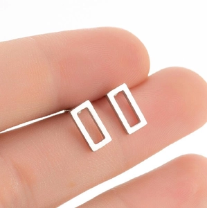 Minimalist silver geometric rectangular stud earrings shown for scale on fingertips