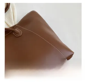 Détail du grand sac cabas en cuir marron avec surpiqûres blanches et texture premium