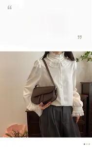 Detail of dark brown saddle bag with leather straps and metal buckles on a model