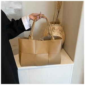 Detail of khaki woven leather tote bag featuring a minimalist large lattice weave pattern