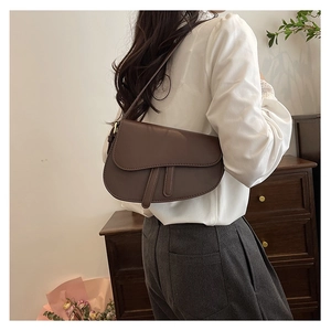 Detail view of a vintage dark brown matte leather saddle bag with antique gold buckle
