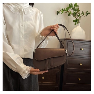 Close-up of a retro dark brown saddle bag with decorative straps in a home setting