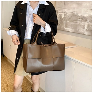 Detail of dark brown woven tote bag showing large leather weave texture and soft structure