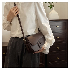 Detail of dark brown vintage saddle bag with matte leather and bronze hardware buckle