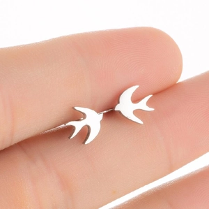 Close-up of mini silver swallow bird stud earrings held between fingertips for size