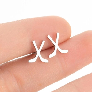 Boucles d'oreilles minimalistes en acier inoxydable en forme de X sur les doigts