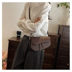 Detailed close-up of a brown matte leather saddle bag featuring iconic leather straps