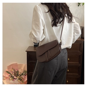 Detailed side view of a vintage brown saddle bag with smooth matte leather and flap closure