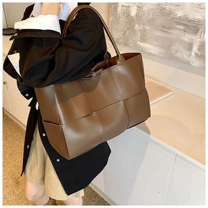 Detail of dark brown woven leather tote with long handles and spacious interior