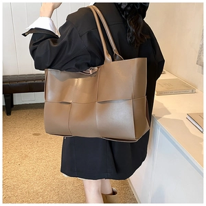 Detailed view of wide woven leather texture on a dark caramel shoulder tote bag
