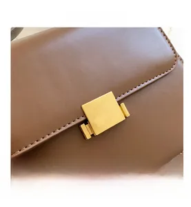 Detailed close-up of premium brown leather bag with elegant gold square metal lock