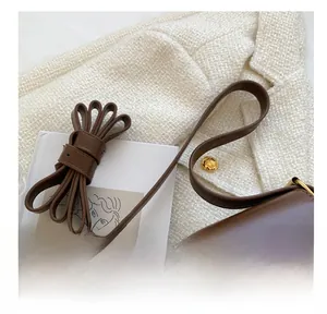 Detail of soft brown leather shoulder strap with metallic buckle on a retro handbag