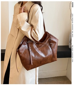 Dettaglio della texture in pelle oleata marrone e fibbia in metallo su borsa tote