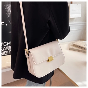Detailed close-up of a minimalist cream crossbody bag with a gold rectangular metal clasp