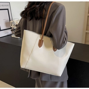 Detail of minimalist leather tote bag featuring brown shoulder strap and fine stitching