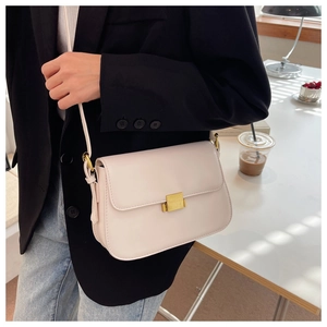 Detail of cream leather crossbody square bag with gold buckle on a stylish model