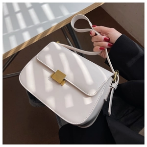 Detail of cream leather shoulder bag with vintage gold square clasp under window light