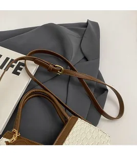 Detail der gewebten Beuteltasche mit braunem Lederbesatz und goldenen Metallteilen