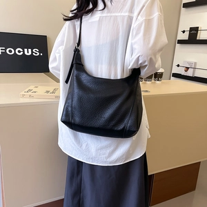Fashionable black pebbled tote bag with adjustable strap shown in a modern interior setting