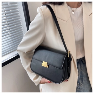 Classic black leather crossbody bag with elegant gold clasp closure shown on a model