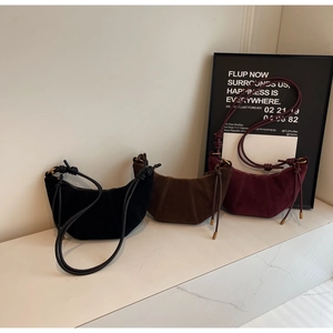 Close-up of suede hobo bags in black, brown, and burgundy with knotted strap details