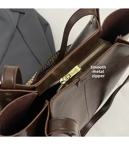 Detailed close-up of smooth metal zipper and textured leather on brown vintage tote bag