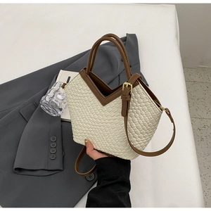 Detail der gewebten Beuteltasche mit braunem Lederbesatz und goldenen Beschlägen