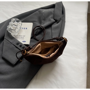 Detail view of dark coffee suede croissant bag showing inner zipper pocket and lining