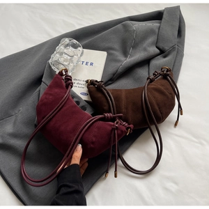 Detailed view of burgundy and dark brown crescent suede bags with decorative stitching