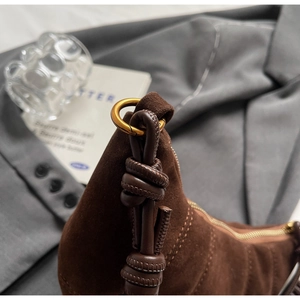 Detail of dark brown suede bag featuring leather knot strap and vintage gold ring buckle