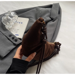 Brown frosted crescent bag with pleated texture on a grey blazer for casual wear