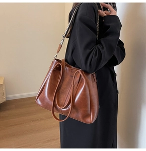 Macro detail of vintage large tote bag with patterned strap on a stylish black coat