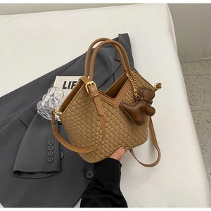 Detail der braunen Web-Eimertasche mit Ledergriff und süßem Bären-Anhänger-Zubehör