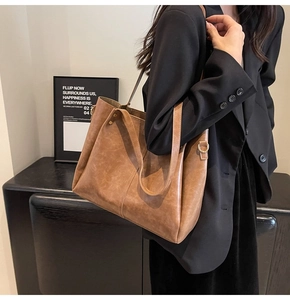 Close-up of vintage brown leather tote bag showing textured finish and gold hardware