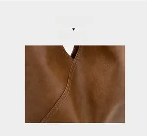 Detail shot of brown leather texture and fine stitching on a vintage tote bag