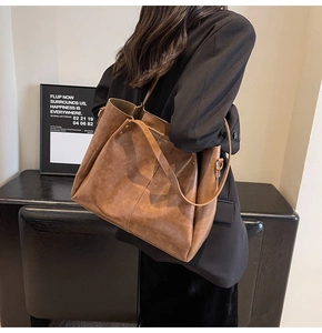 Brown vintage large capacity tote bag shown on model with textured wide shoulder strap