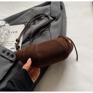 Macro detail of dark brown suede crescent bag with curved stitching and gold hardware