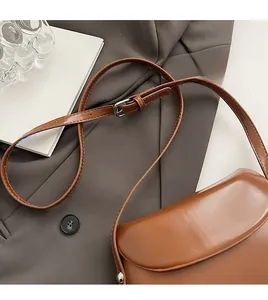 Détail de la bandoulière réglable en cuir sur un sac besace marron vintage