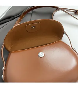 Détail du fermoir magnétique argenté sur un sac à bandoulière marron en cuir