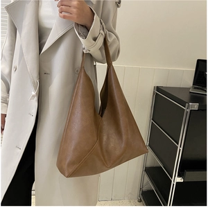 Detail view of large brown soft leather hobo bag worn by a model for daily commute